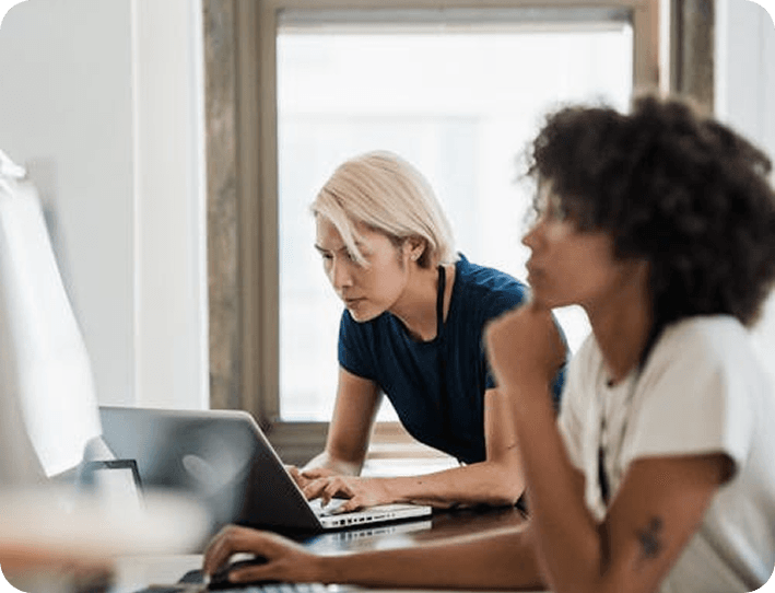 Team members collaborating at a laptop in a bright office